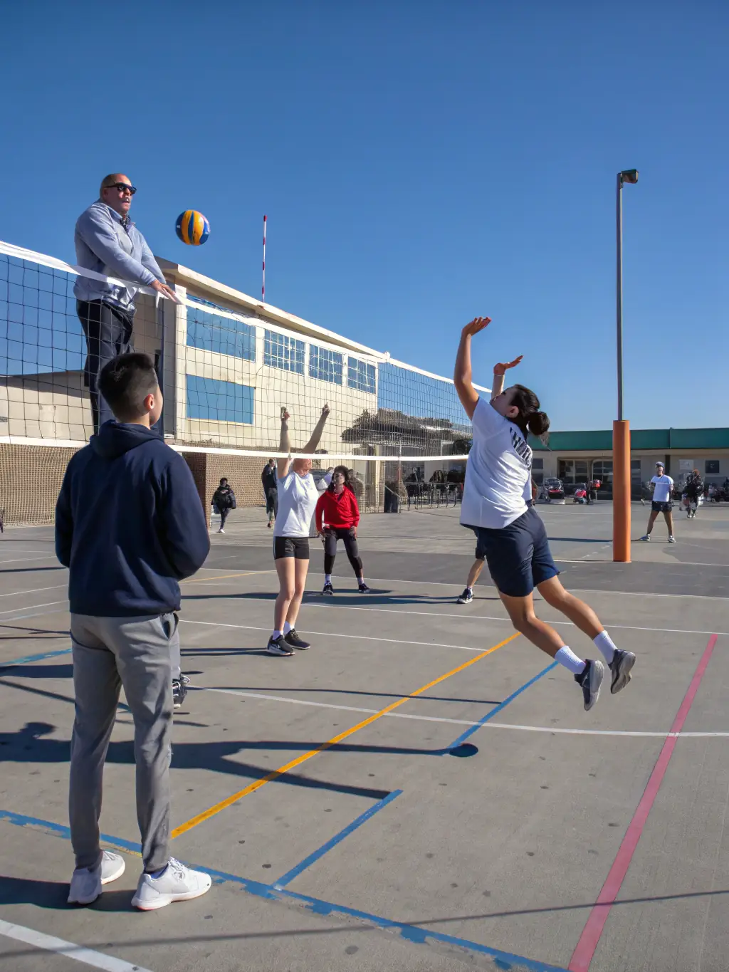 A group of students participating in a volleyball match outdoors, emphasizing agility and coordination.